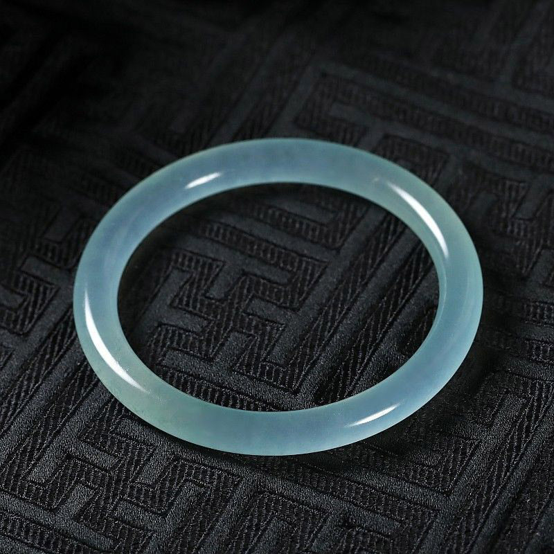 Hellgrünes Jade Armband auf schwarzem Stoff elegant präsentiert.