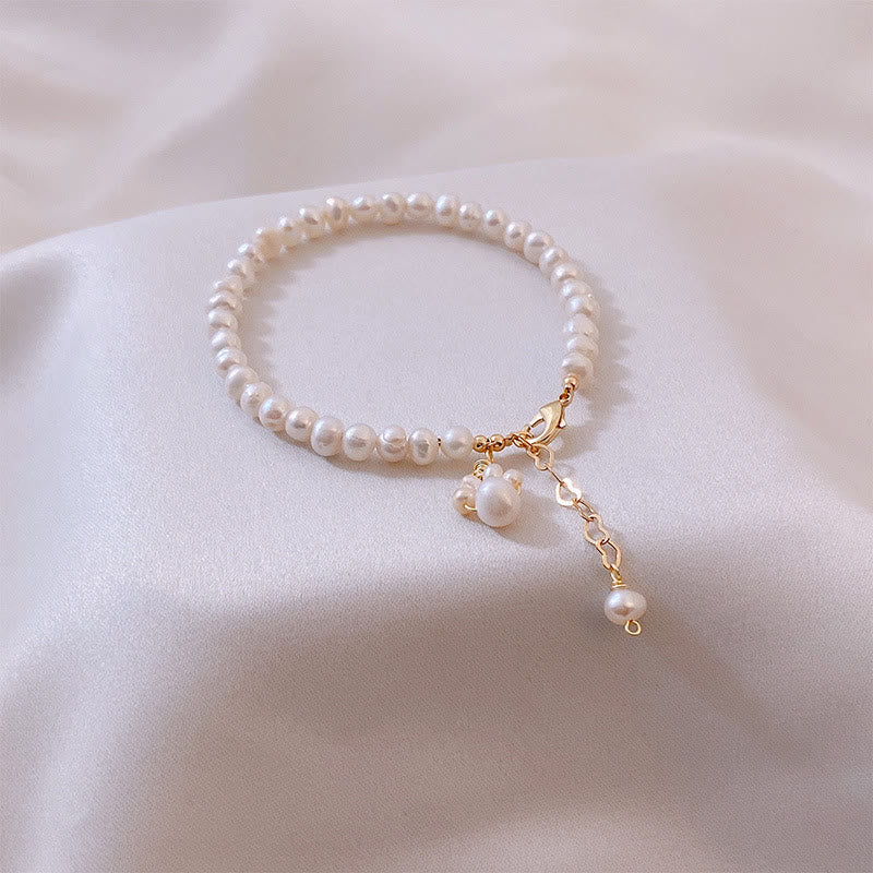 Elegantes Perlenarmband mit goldener Schließe und Perlenanhängern.