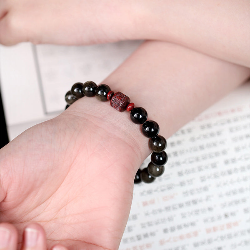 Schwarzes Obsidian Armband mit rotem Om Mani Padme Hum Anhänger am Handgelenk