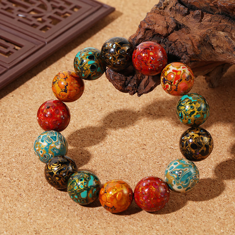 Buntes Armband mit lackierten Perlen auf Sand, Naturstein Ruhe.