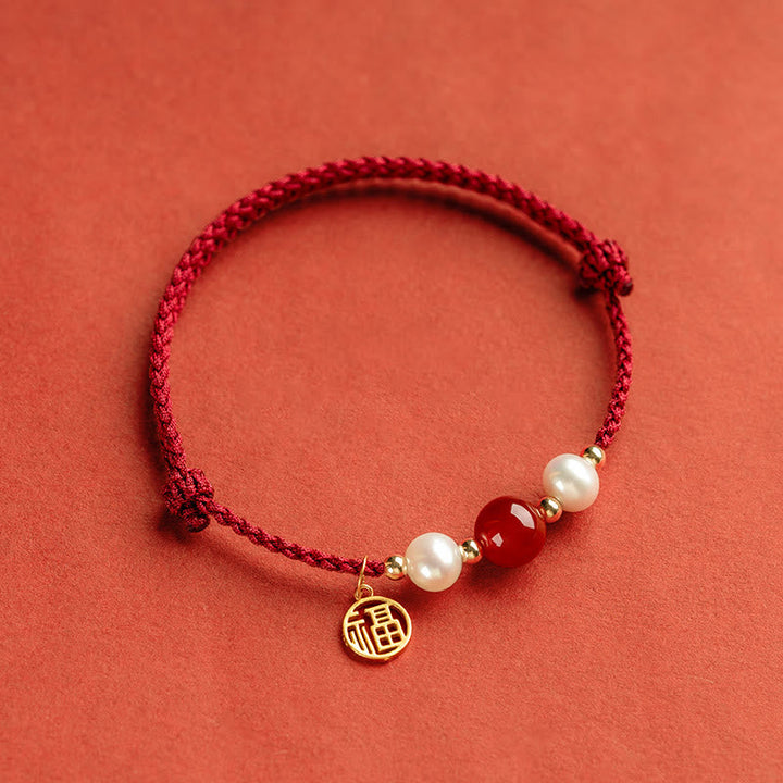 Rotes Armband mit Perlen und goldenem Fu-Zeichen Anhänger elegant.