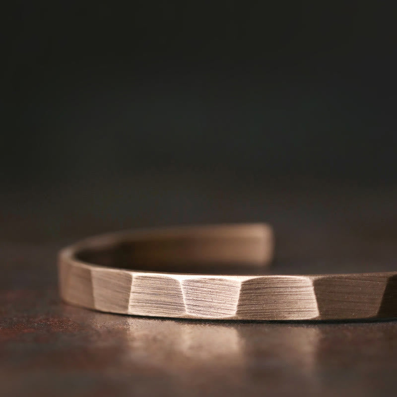 Kupfer Armband mit geometrischem Design auf dunklem Untergrund.