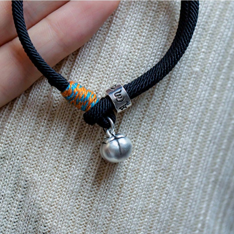 Schwarzes Armband mit silbernem Om-Anhänger und orangefarbener Wicklung.