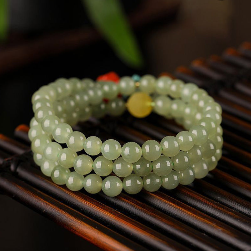 Hellgrünes Jade Armband mit glänzenden Perlen auf Holzoberfläche.