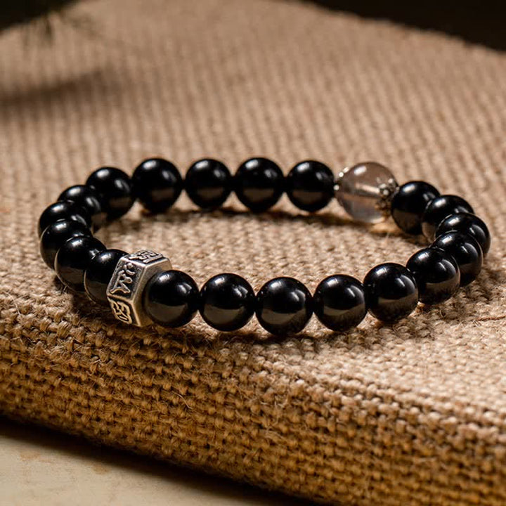 Schwarzes Obsidian Armband mit Silber Verschluss auf Stoffhintergrund