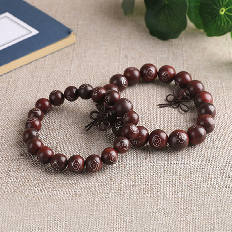 Sandelholz Armband mit Om Symbol Perlen auf beigem Leinen displayed.