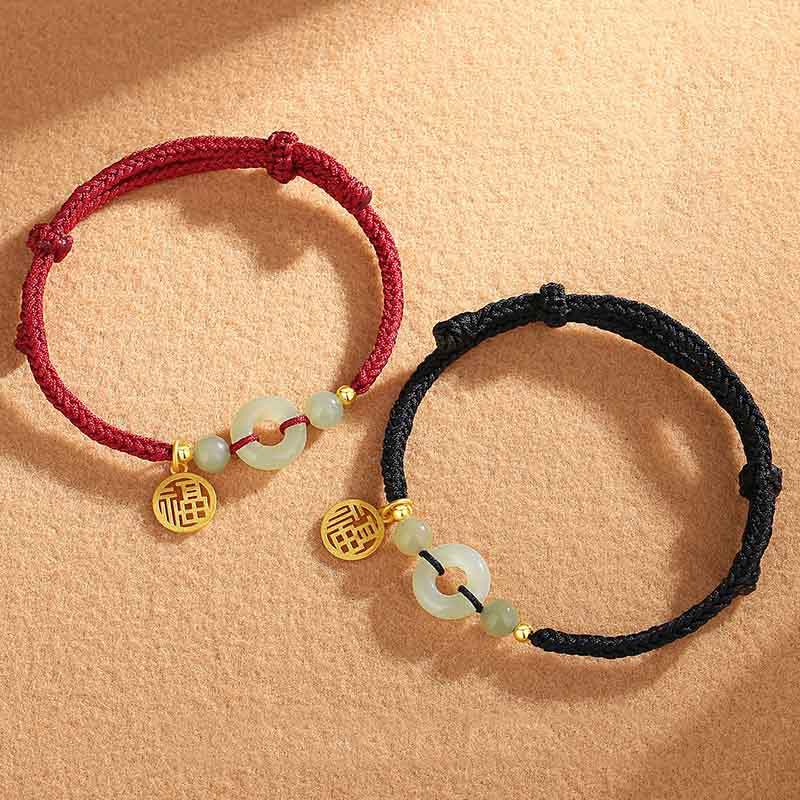 Zwei Jade Armbänder mit goldenen Fu-Zeichen Anhängern elegant präsentiert.