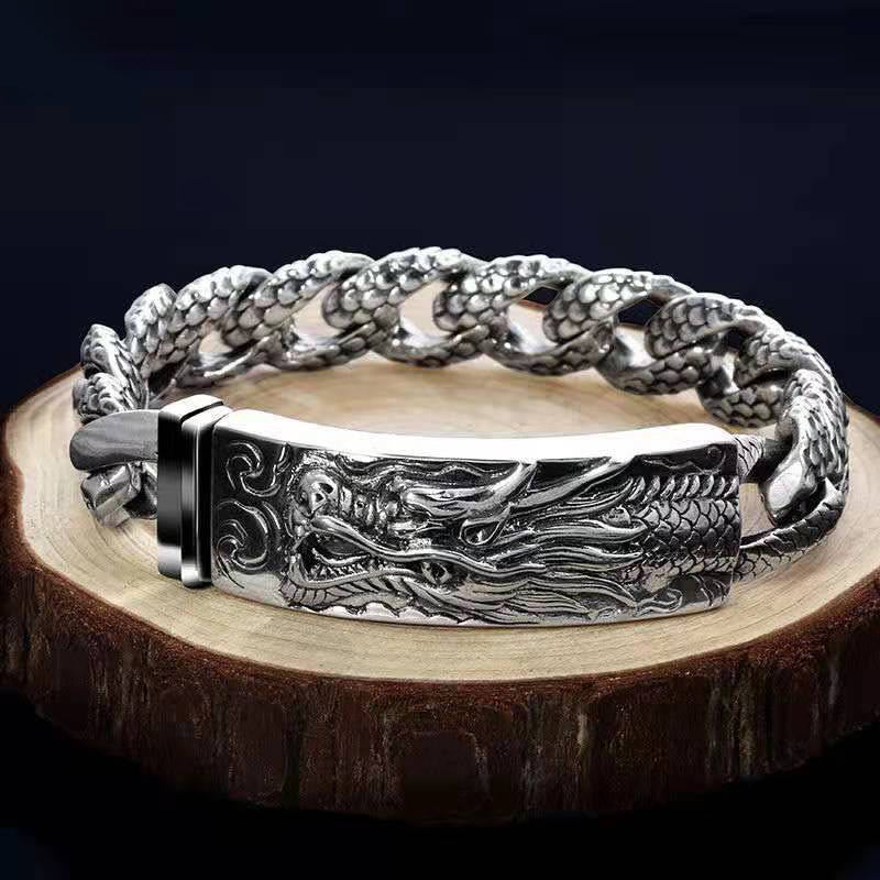 Silbernes Drachen Armband mit detaillierter Gravur auf Holz.