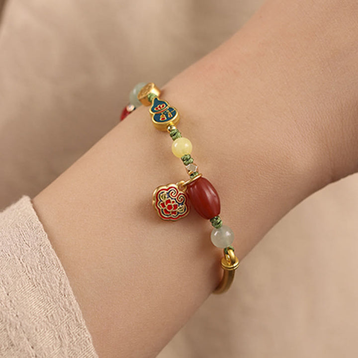 Armband Auspicious – Glück & Wohlstand mit roten Steinen und goldenen Elementen am Handgelenk.