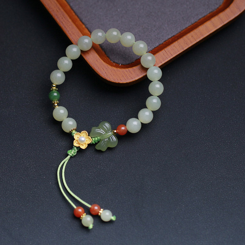 Jadegrünes Armband mit Schmetterlingsanhänger auf Holzständer präsentiert.