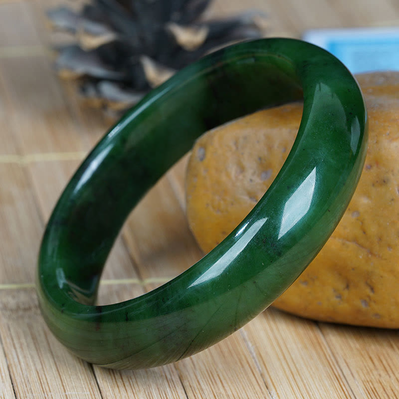 Grünes Jade Armband glänzend poliert auf Holzoberfläche Nahaufnahme.