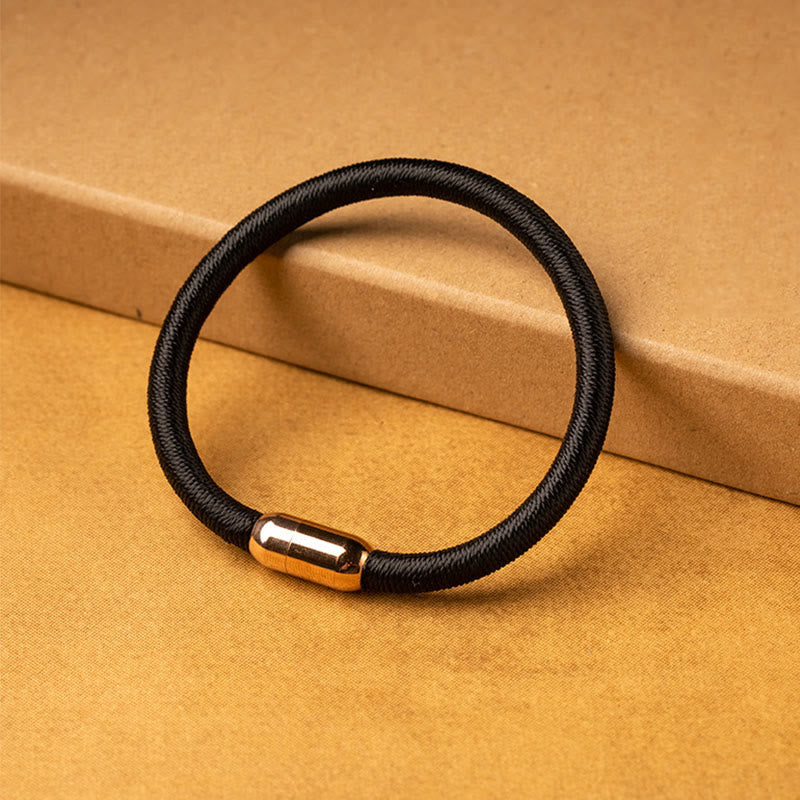 Schwarzes magnetisches Armband mit goldenem Verschluss auf gelbem Hintergrund