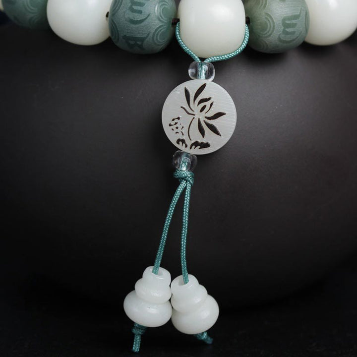 Armband Weiße Jade mit Om-Anhänger, Bodhi-Perlen, türkises Seil, Detailaufnahme.