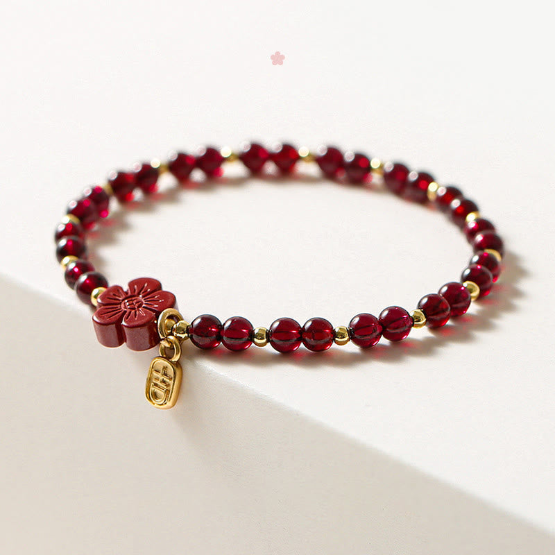 Rotes Granat Armband mit Blütenanhänger auf weißem Untergrund