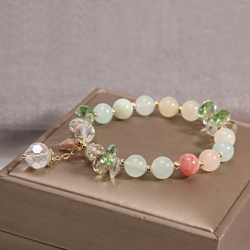 Elegantes Kristall-Armband mit grünen und rosafarbenen Steinen auf Schmuckbox.