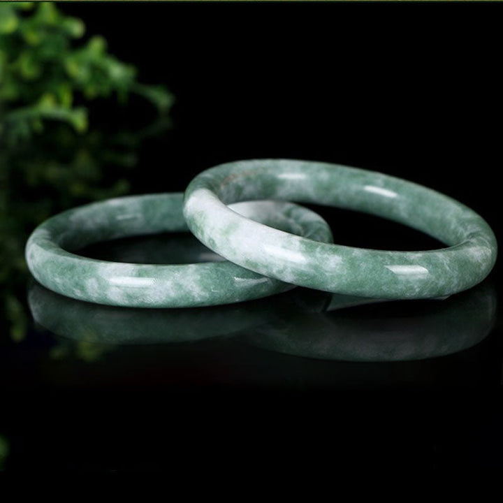 Zwei grüne Jade Armbänder nebeneinander auf schwarzem Hintergrund glänzend.
