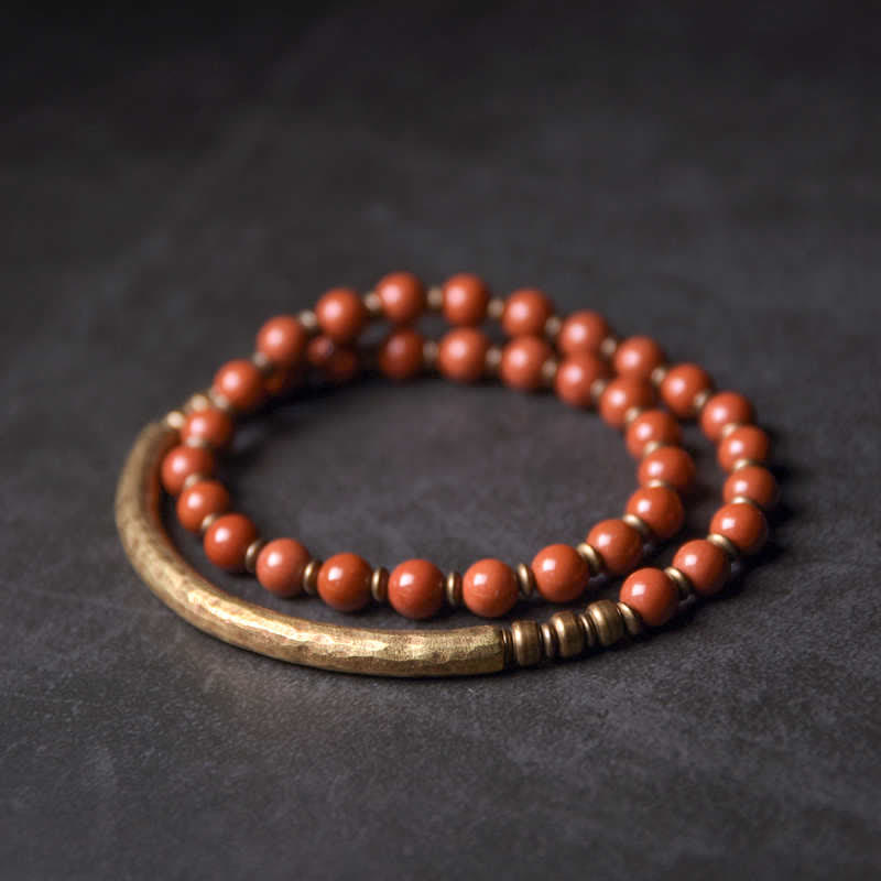 Rotes Perlen Armband mit Holzelement auf dunklem Hintergrund Detailaufnahme