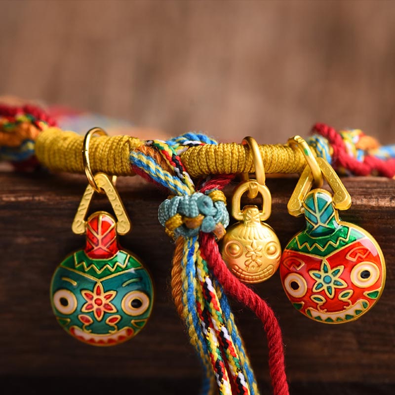 Buntes Armband mit goldenen Glücksbringern und Seidenfäden elegant drapiert.