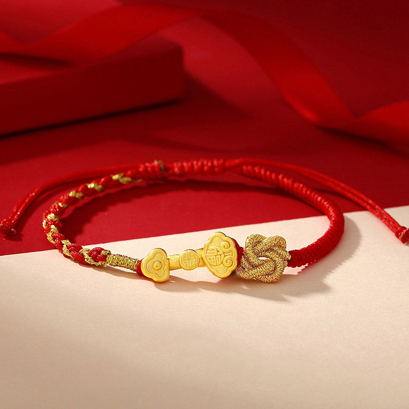 Rotes Armband mit goldenen Glückssymbolen und Löwenkopf Charm.
