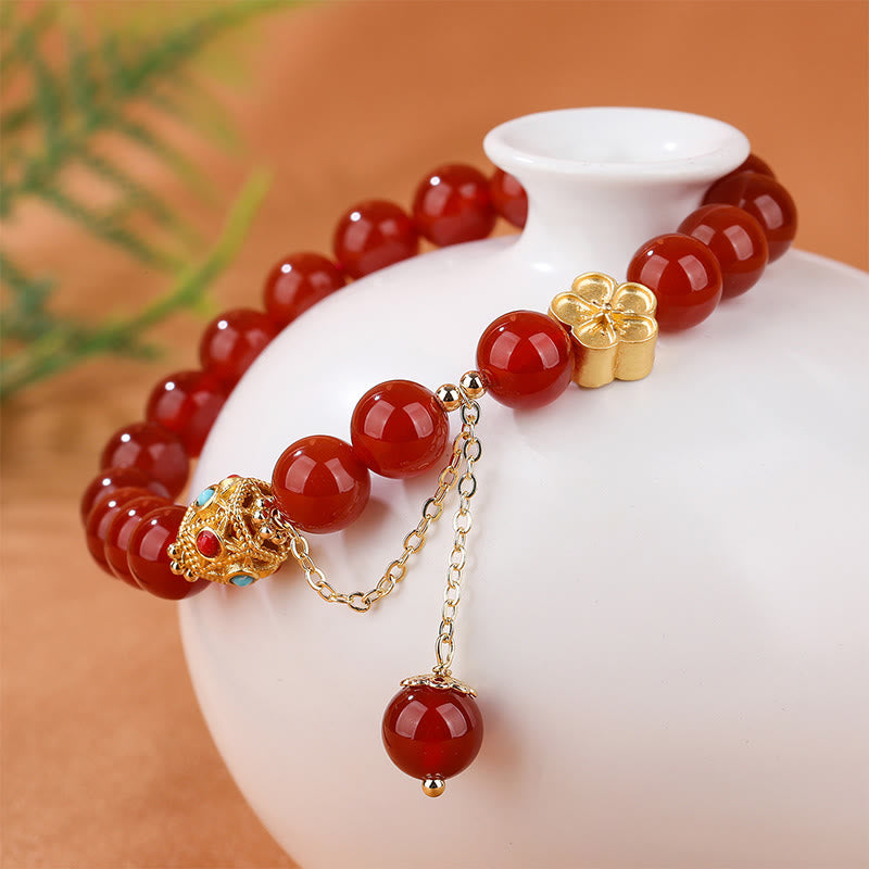 Armband Roter Achat Pfirsichblüte mit goldenen Perlen elegant präsentiert.