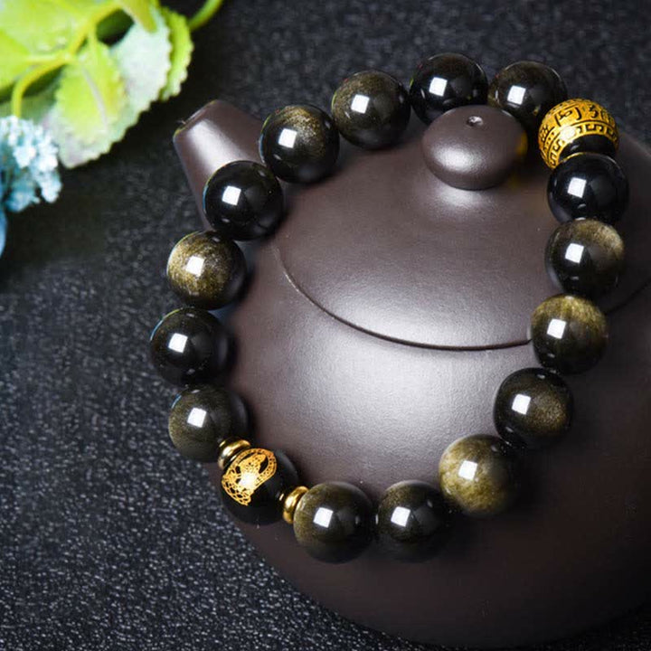 Obsidian Armband mit goldenen Perlen auf grauem Hintergrund elegante Deco