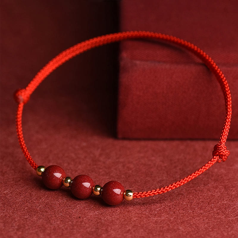 Rotes Armband Zinnober – Glück & Segen mit Perlen auf rotem Untergrund