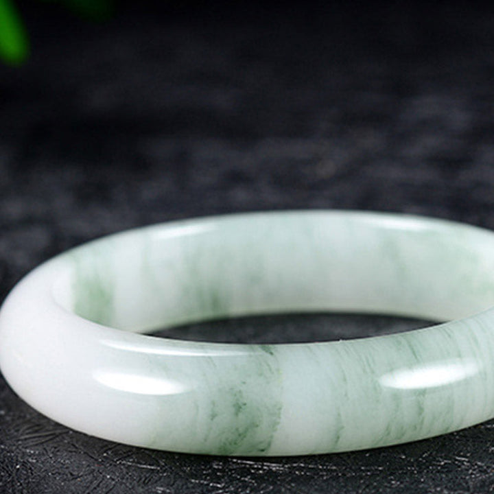 Jadegrünes Armband mit Glückssteinen elegant auf dunklem Hintergrund präsentiert.