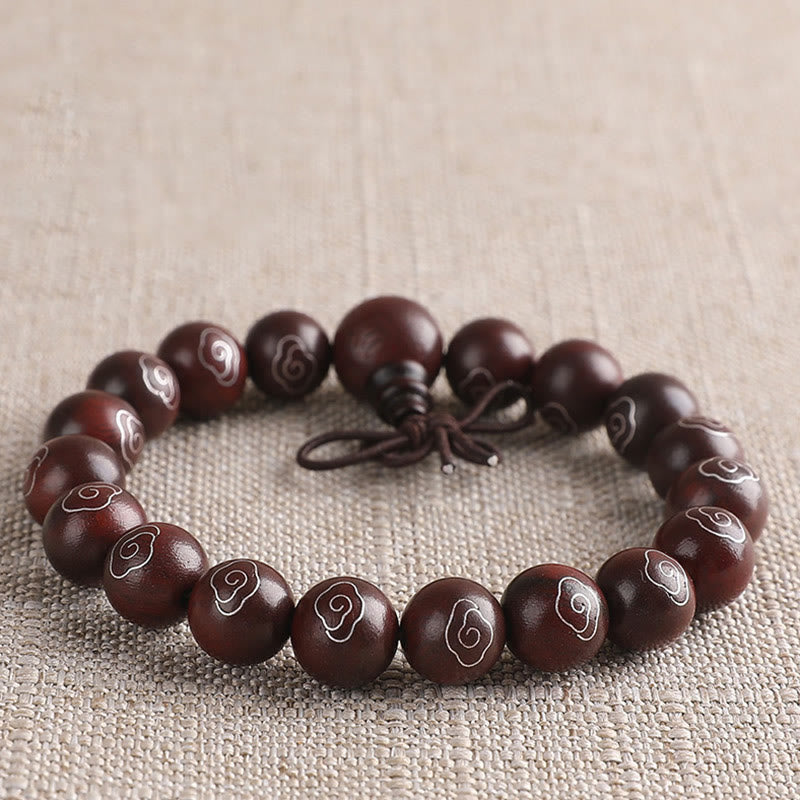 Dunkelbraunes Sandelholz Armband mit Om Symbol auf Leinenstoff.