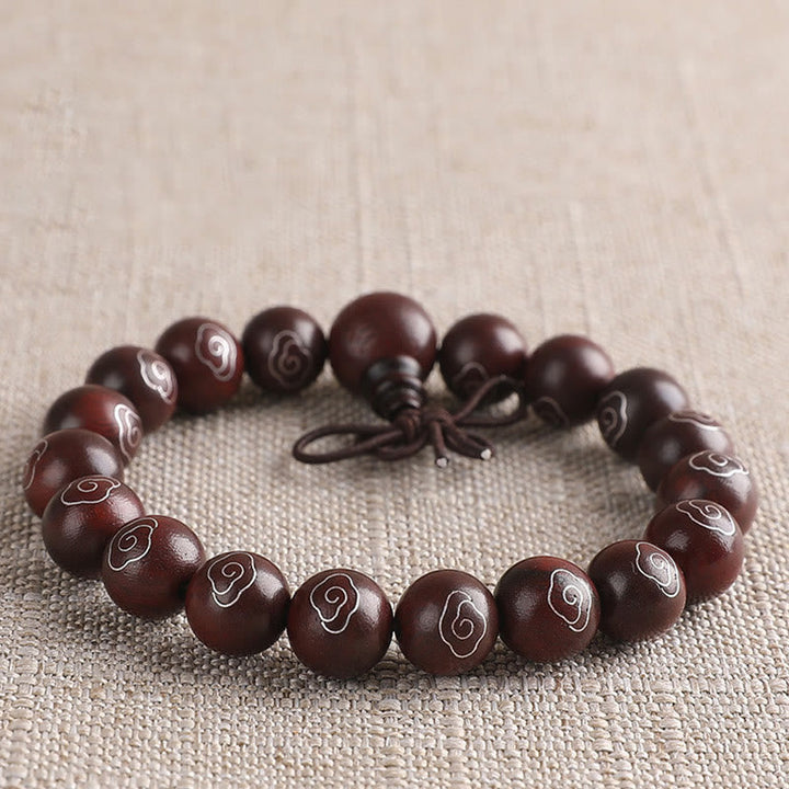 Dunkelbraunes Sandelholz Armband mit Om Symbol auf Leinenstoff.