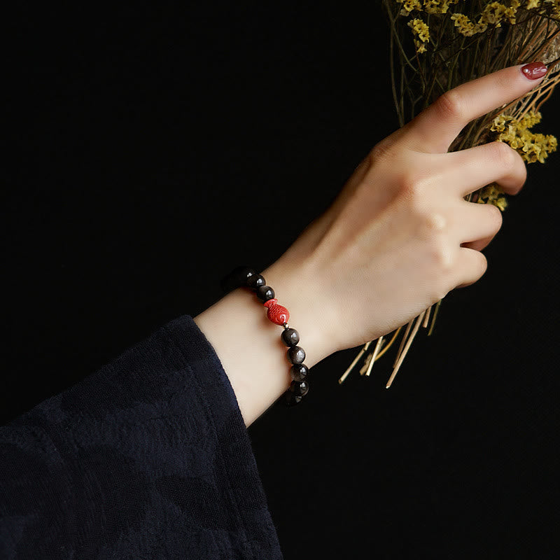 Armband mit schwarzem Obsidian und roten Perlen am Handgelenk getragen