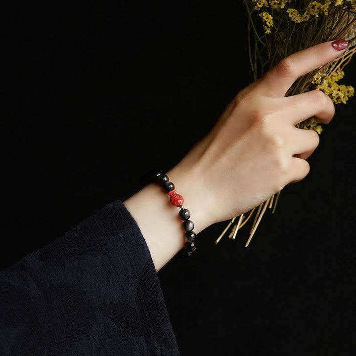 Armband mit schwarzem Obsidian und roten Perlen am Handgelenk getragen