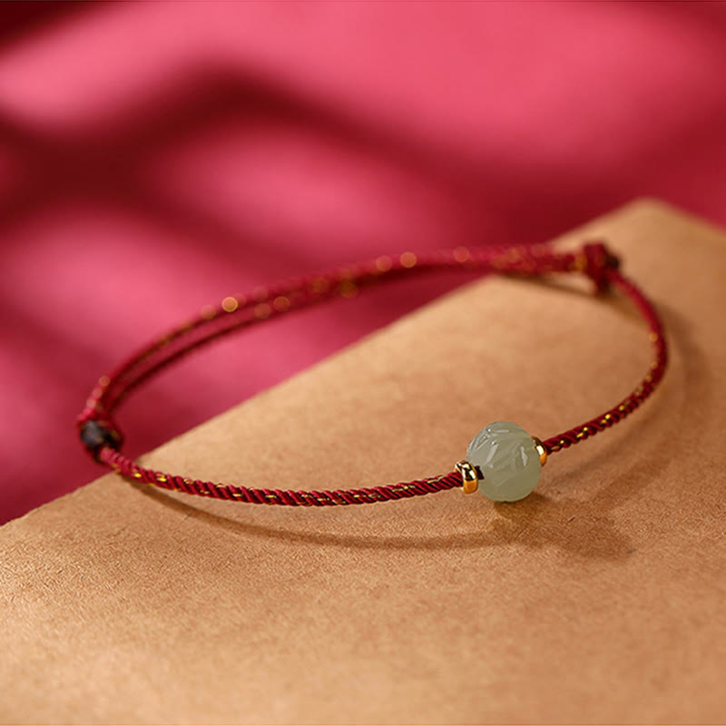 Rotes Armband mit Jade Lotus Anhänger am Handgelenk getragen