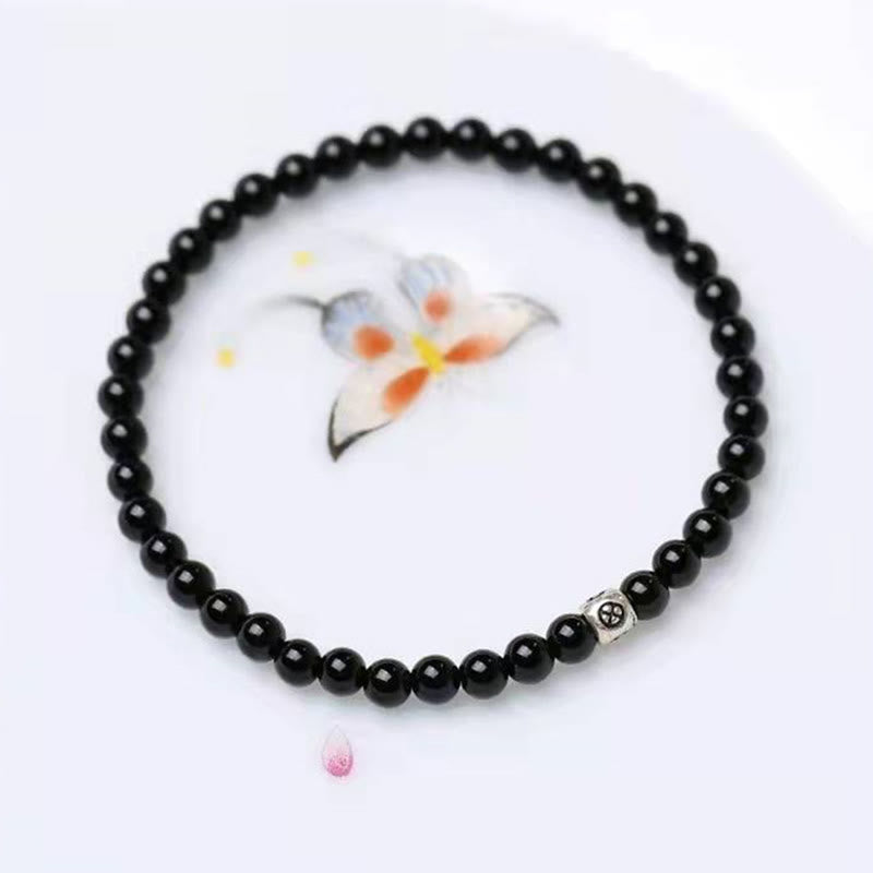 Schwarzer Obsidian Armband mit silbernem Katzen-Charm auf weißem Hintergrund