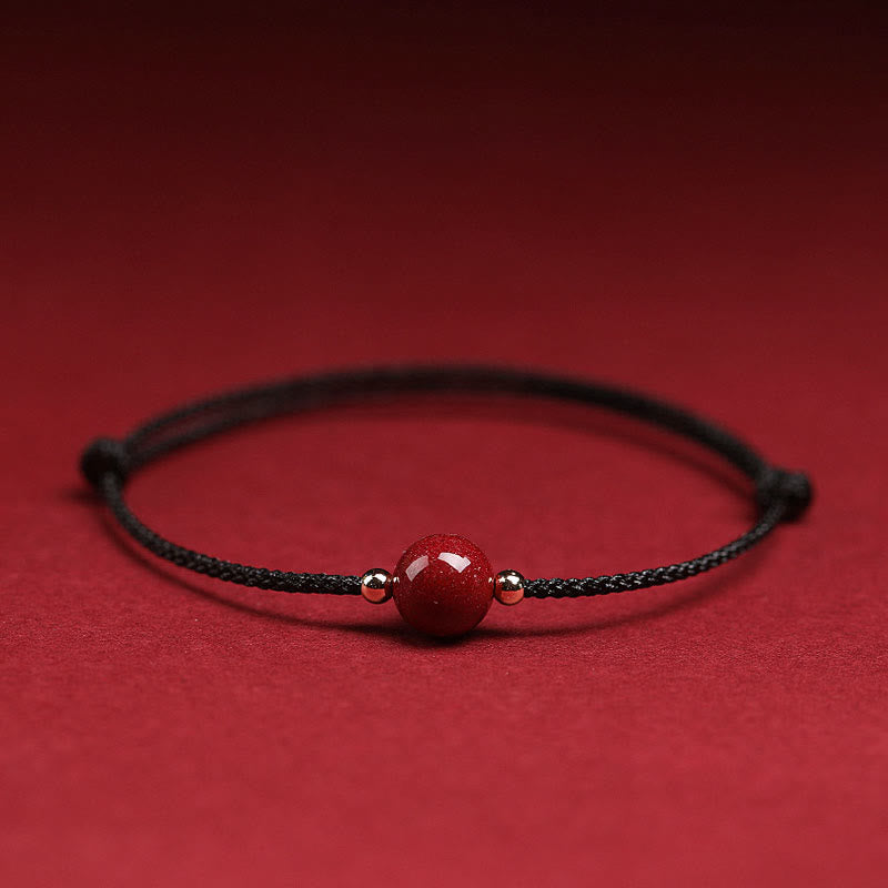 Armband Zinnober – Glück & Segen mit rotem Stein auf rotem Hintergrund