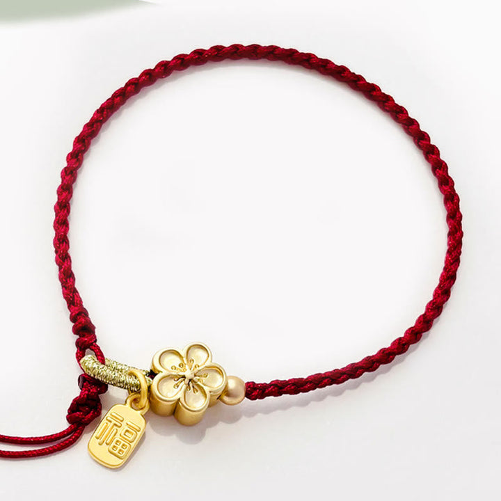Rotes Armband Pfirsichblüte Glück Energie goldene Charms elegant geflochten.
