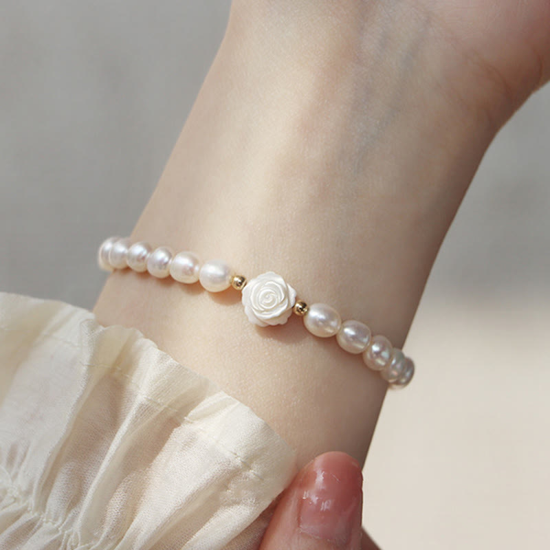 Elegantes Perlenarmband mit weißer Blüte am Handgelenk getragen, Aufrichtigkeit.