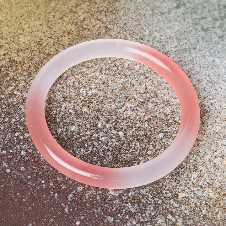 Rosafarbenes Seiden-Jade Armband Armreif auf glitzerndem Untergrund Nahaufnahme