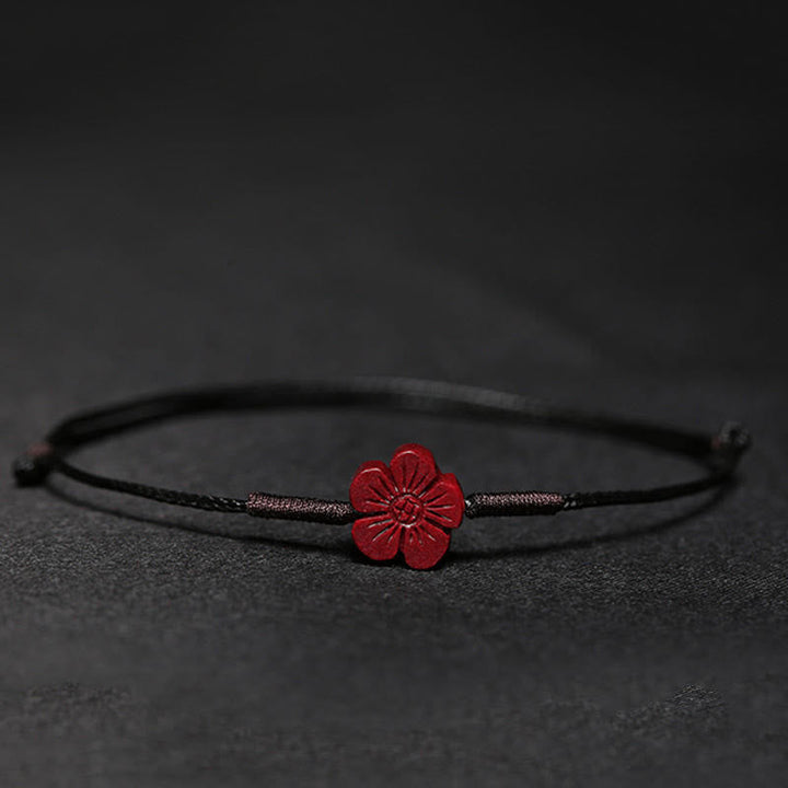 Rotes Blüten Armband auf grauem Hintergrund, schwarzes elastisches Textilband