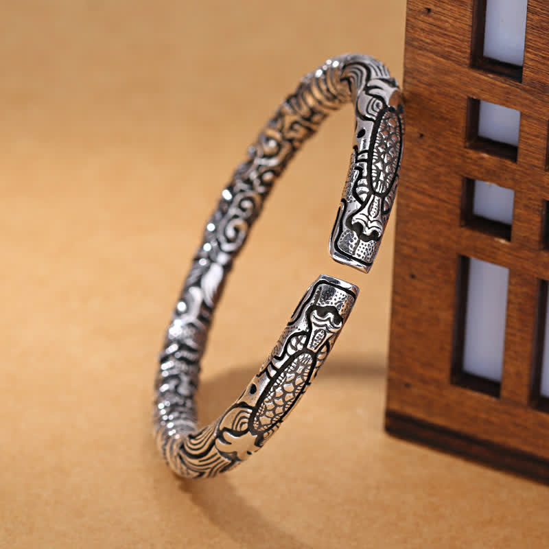 Silbernes Drachen-Armband mit ornamentalen Mustern elegant präsentiert.