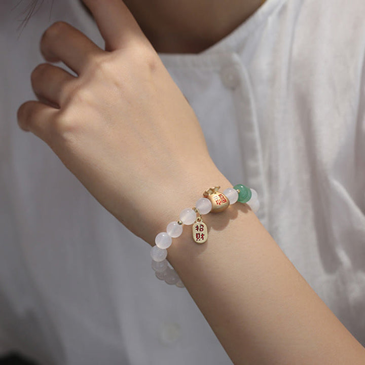 Armband mit weißen Perlen und grünem Stein am Handgelenk getragen