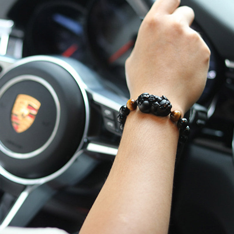 Armband Tigerauge Obsidian Pixiu am Handgelenk im Auto getragen