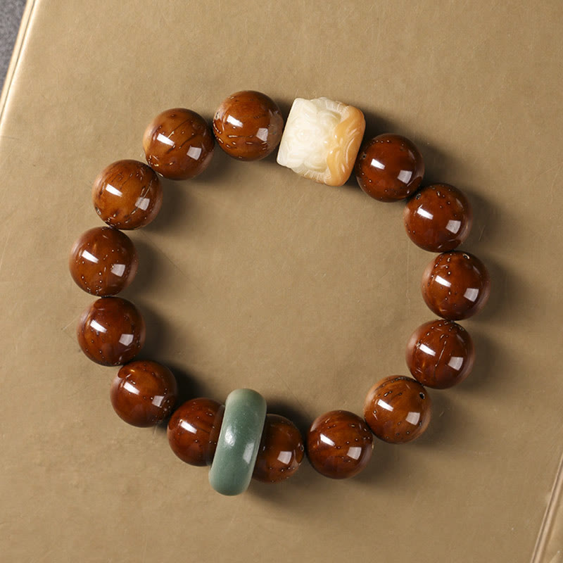 Armband mit braunen Perlen und Jade Akzenten auf beigem Hintergrund.