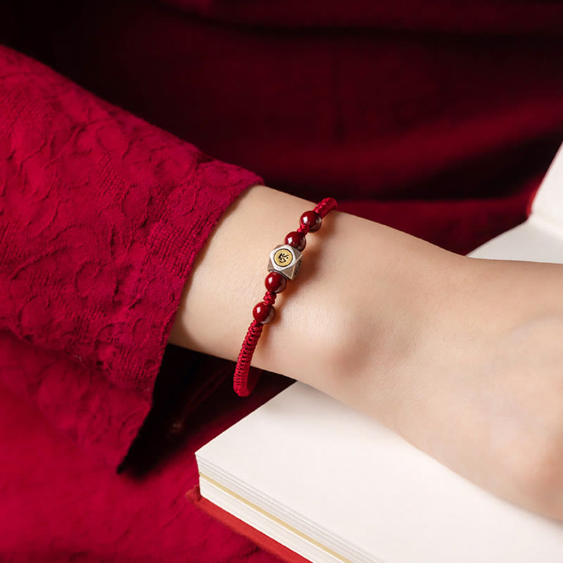 Rotes Armband mit Perlen und silbernem Anhänger am Handgelenk getragen.