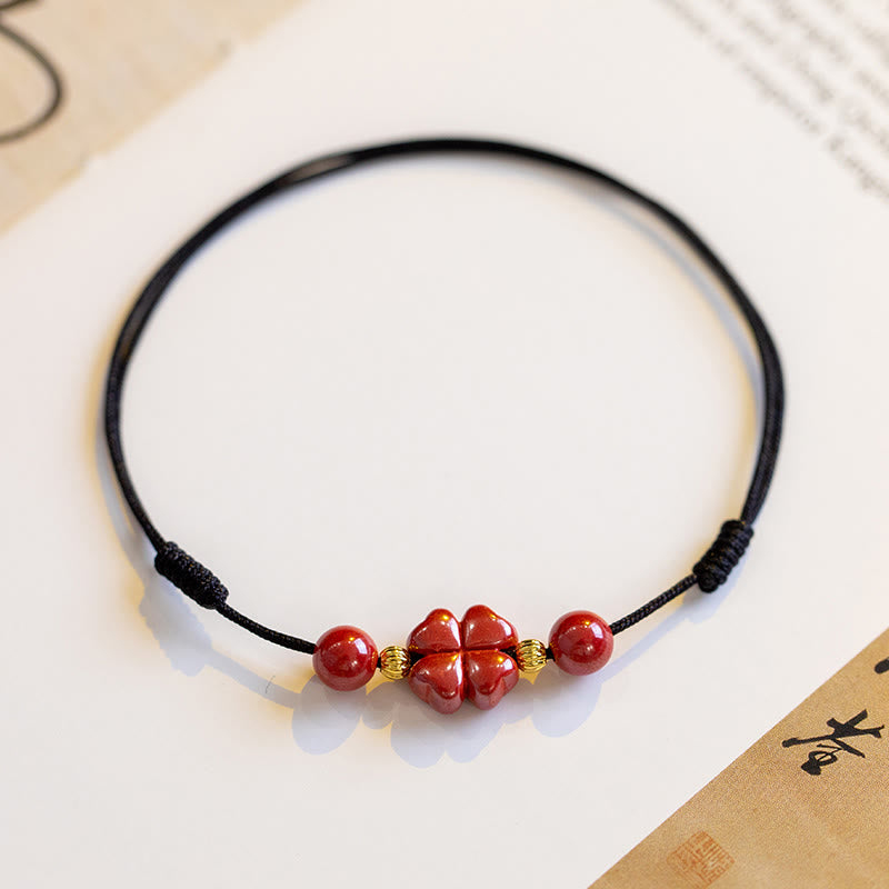 Armband Zinnober Kleeblatt rotes Naturstein-Perlenarmband schwarze Kordel Nahaufnahme