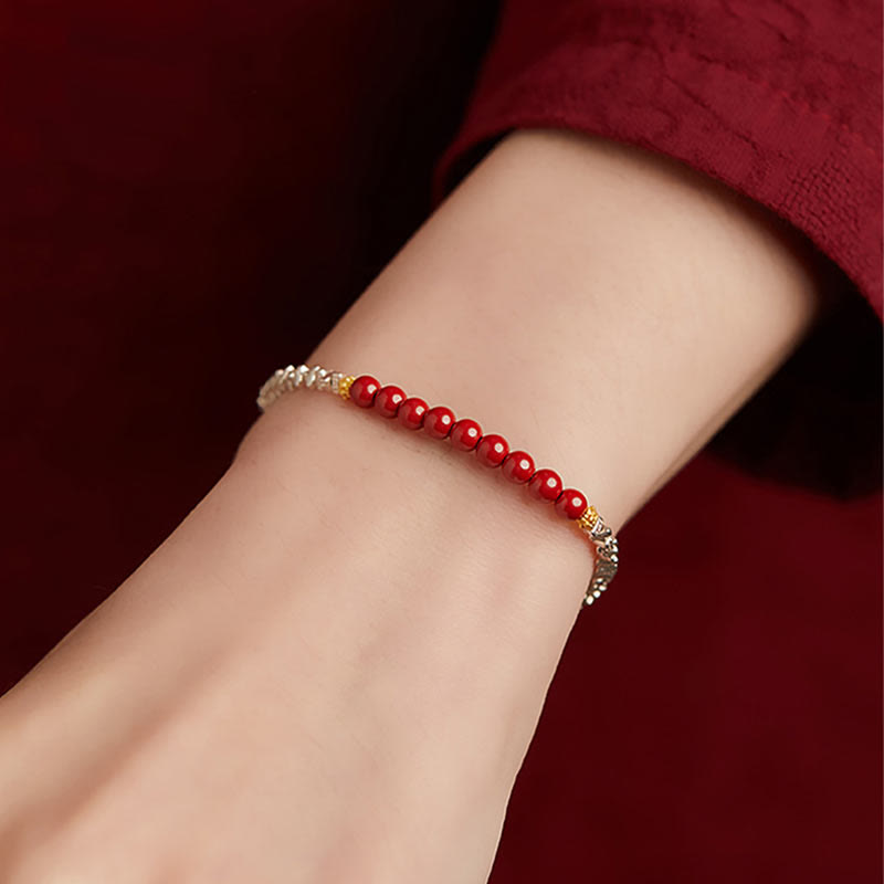Rotes Armband mit silbernen Perlen am Handgelenk getragen elegant.