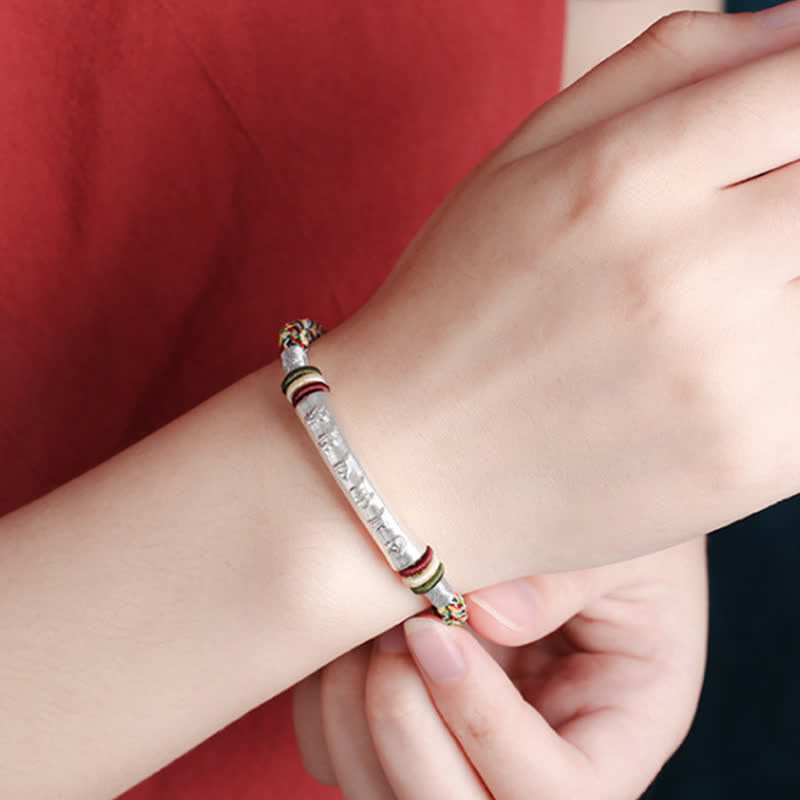 Armband 925 Silber Om Mani Padme Hum am Handgelenk mit roten Akzenten getragen.