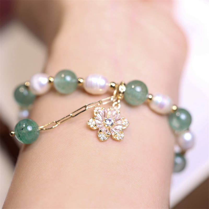 Armband mit grünem Jade, Perlen und Blütenanhänger am Handgelenk getragen