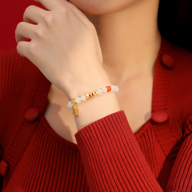 Armband mit weißer Jade und Koi Fisch am Handgelenk getragen rot.