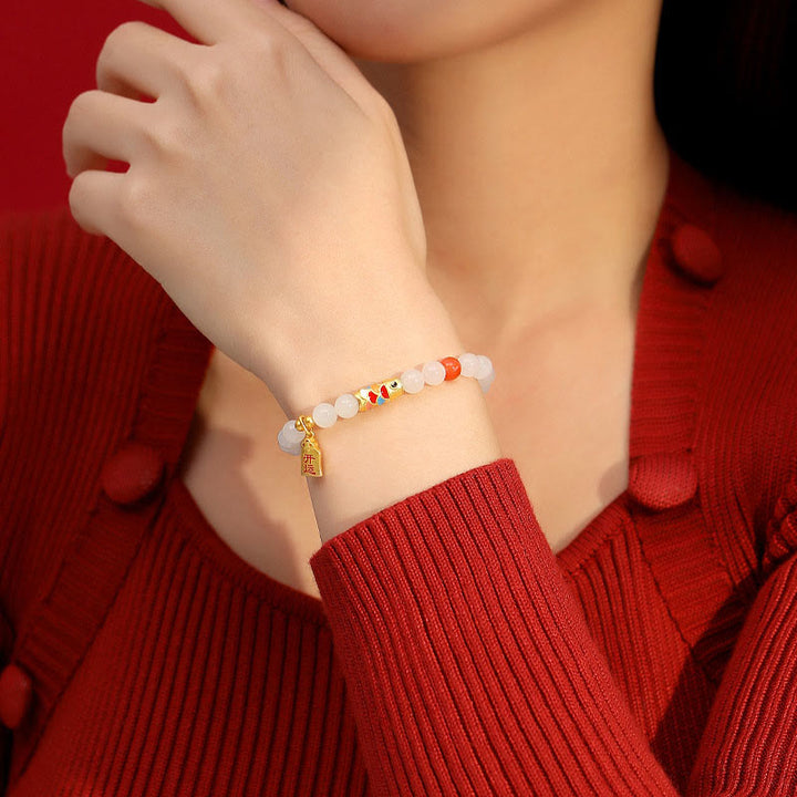 Armband mit weißer Jade und Koi Fisch am Handgelenk getragen rot.