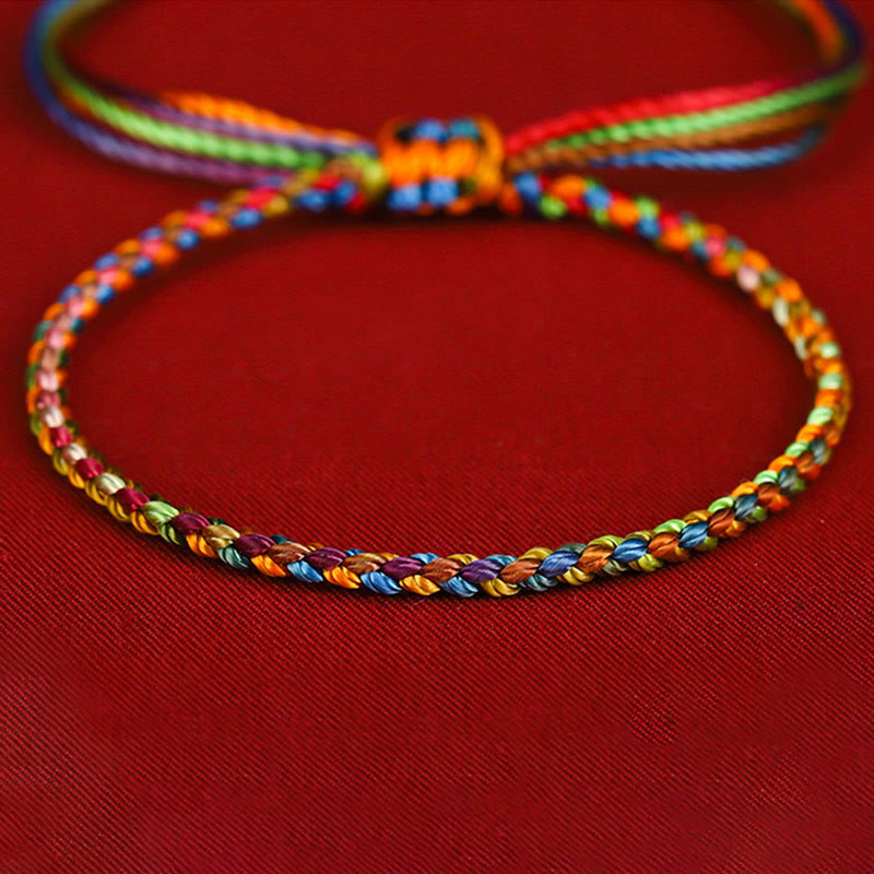 Buntes Glücksarmband mit Regenbogenfäden auf rotem Hintergrund, Nahaufnahme